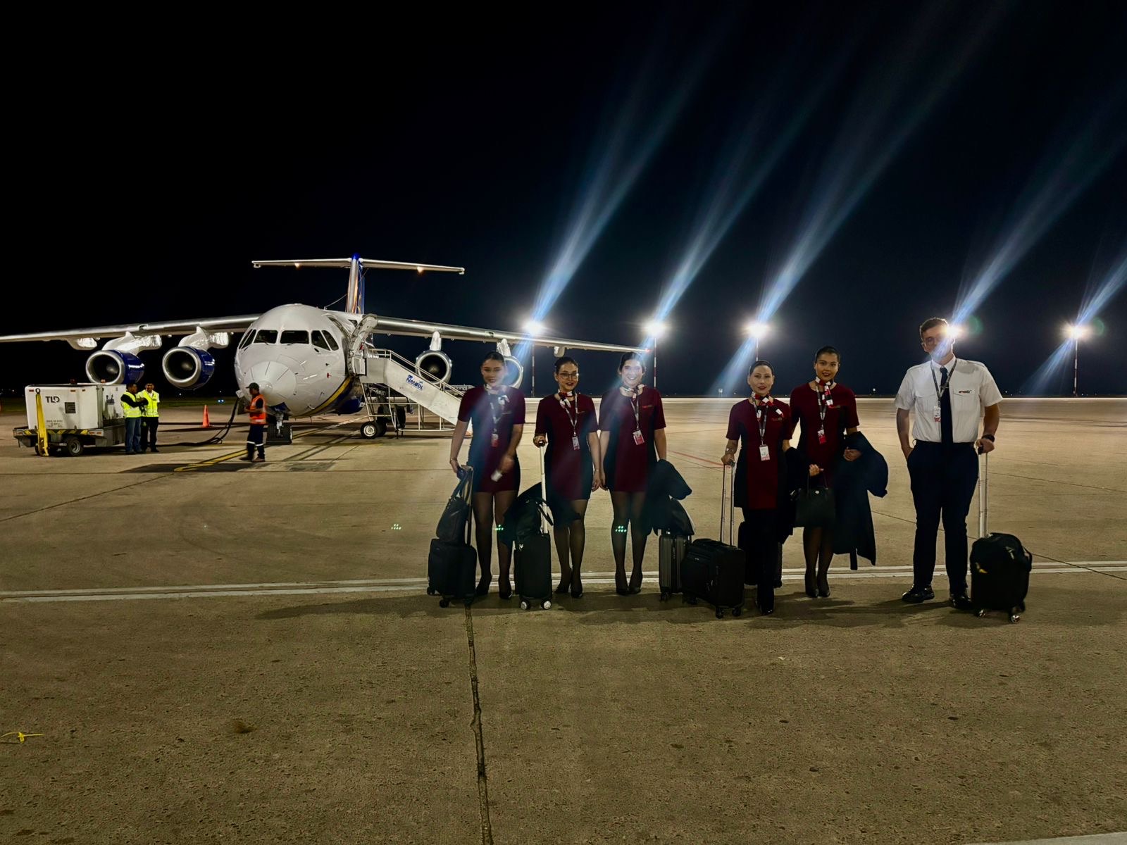 Tripulantes de cabina y piloto de AMASFLY junto a una aeronave, de noche