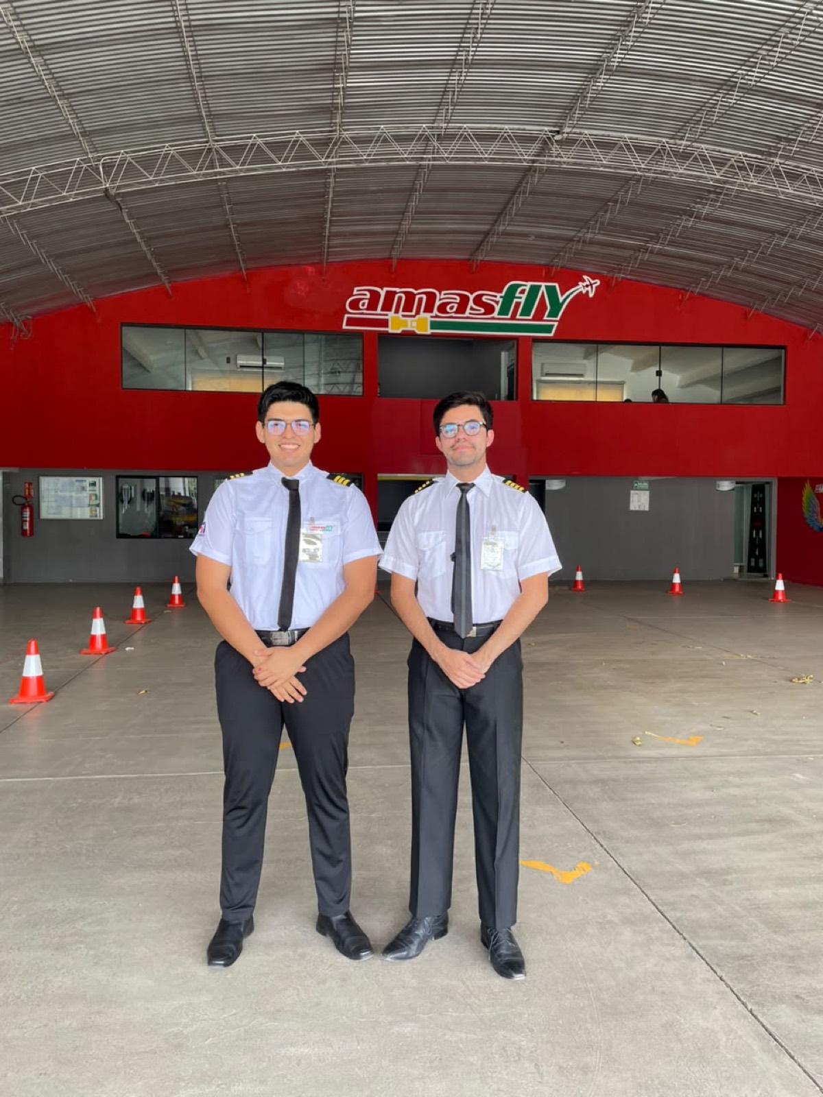 Dos alumnos piloto de uniforme frente al hangar AMASFLY